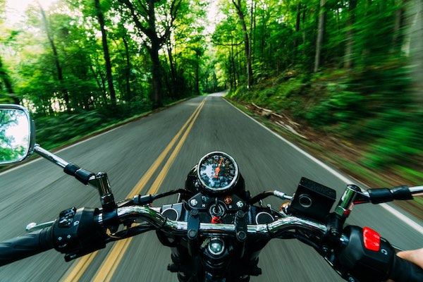 Motorcycle from rider's perspective on road indicating rapid progress